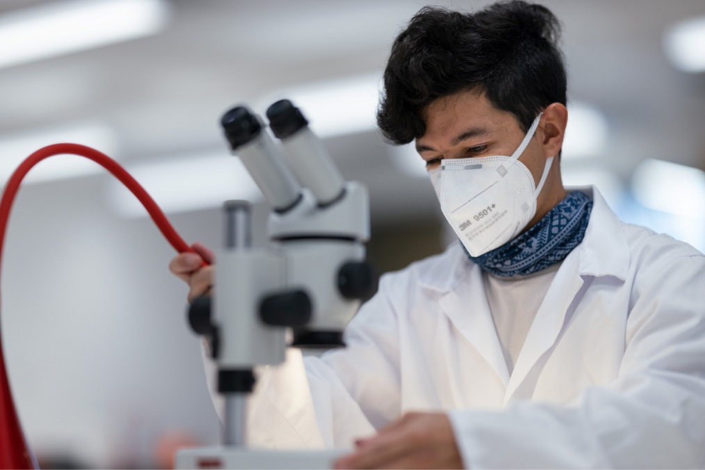 Student wearing a lab coat and mask 